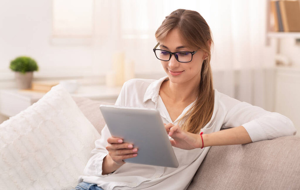 Lady Using Digital Tablet Sitting On Couch Indoor - 写真・画像