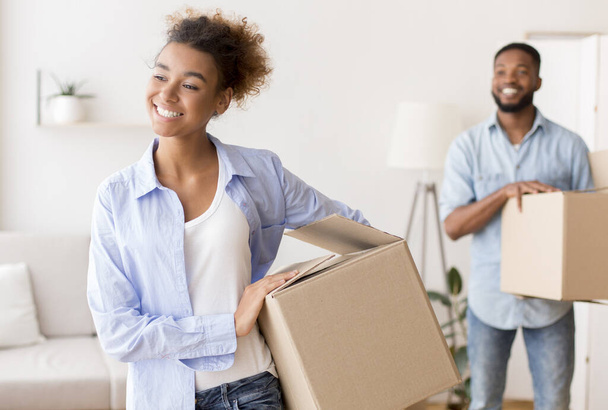 gelukkig zwart echtgenoten dragen verpakt dozen in nieuwe appartement - Foto, afbeelding