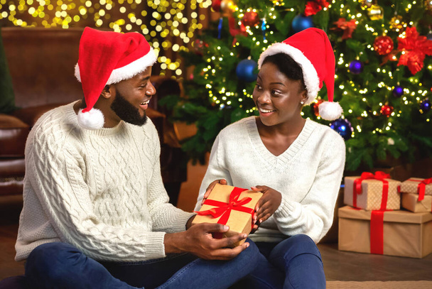 Happy afro woman receiving Christmas present from her loving husband - 写真・画像