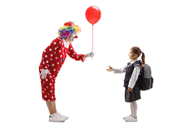 Clown giving a red balloon to a schoolgirl - Foto, Bild