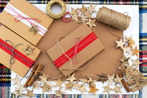 Fondo de Navidad con cajas de regalo, mechones de cuerda, rools de papel y decoraciones sobre artesanía. Preparación para las vacaciones. Vista superior
. - Foto, Imagen