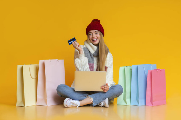 Cheerful winter girl recommending credit card for shopping online - Photo, Image