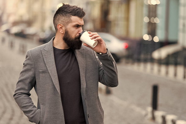 Delicious drink. Man bearded hipster drink coffee paper cup. Businessman well groomed enjoy coffee break outdoors urban background. Prefer coffee on the go. Thoughtful but relaxed. Take self care - Photo, Image