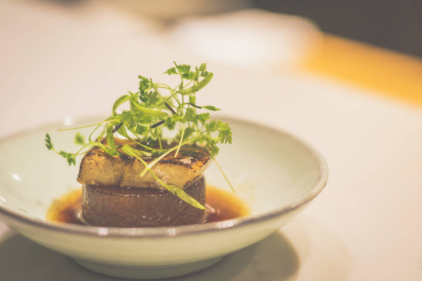 Daikon brasato con foie gras di anatra in una ciotola di porcellana
 - Foto, immagini