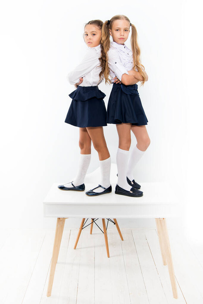 Providing children with education. Small children standing on table in classroom. Little children enjoying school break. Cute children with long hair wearing school uniform with fashion look - Photo, image