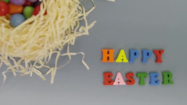 Focus pull of wooden letters spelling out “Happy Easter” next to a nest with easter eggs - Imágenes, Vídeo