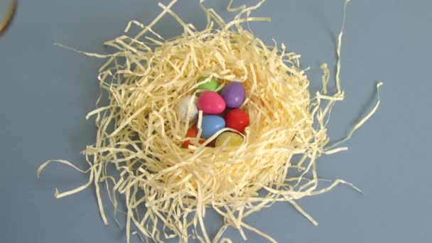 Holding a magnifying glass over colourful candy Easter eggs in a nest - Filmmaterial, Video