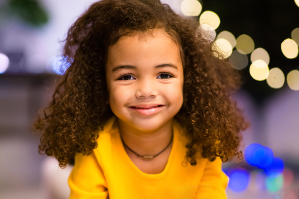 Portrait of adorable little african girl, christmas lights - Photo, Image