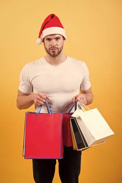 The morning before Xmas. man in santa hat hold christmas present. delivery christmas gifts. happy santa man on yellow background. online christmas shopping. Happy new year. Christmas composition - Fotografie, Obrázek