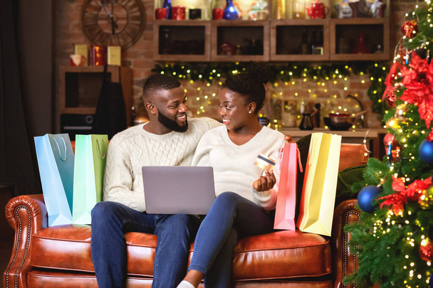 Cheerful afro couple buying Christmas gifts online - Photo, Image