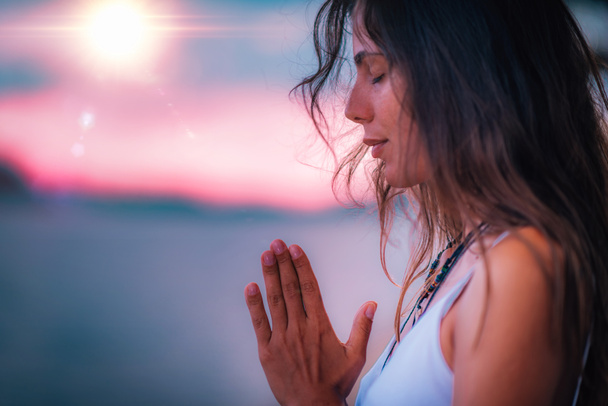 Jeune femme méditant les yeux fermés, pratiquant le Yoga avec les mains en position de prière
.   - Photo, image