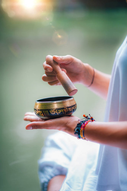 Закрыть изображение женских рук, держащих Тибетскую чашу у воды
  - Фото, изображение