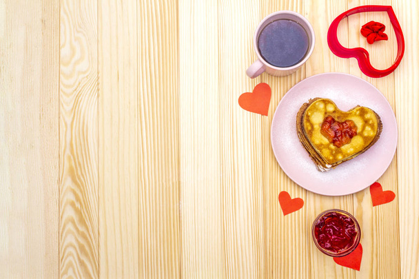 Naleśniki w kształcie serca na romantyczne śniadanie z dżemem truskawkowym i czarną herbatą. Koncepcja shrovetide (karnawał). Na drewnianym tle, widok z góry - Zdjęcie, obraz