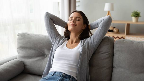 Relaxed serene young woman lounge on comfortable sofa at home - Foto, Imagen