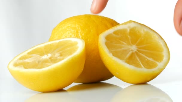 reife frische saftige gelbe Zitrone auf weißem Hintergrund. weibliche Hand nimmt reife Zitrone - Filmmaterial, Video