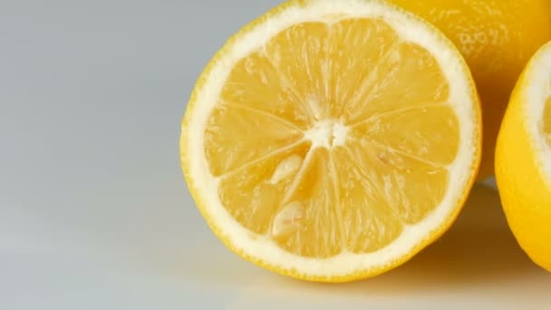 Зрізати свіжий соковитий жовтий лимон на білому тлі обертається
 - Кадри, відео