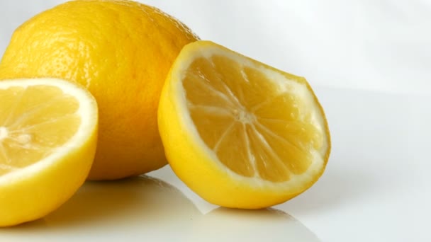 Зрізати свіжий соковитий жовтий лимон на білому тлі обертається
 - Кадри, відео
