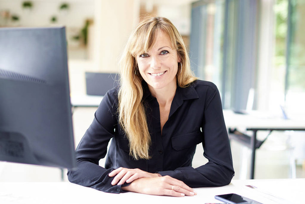 Smiling businesswoman looking at camera and smiling while sittin - Photo, image