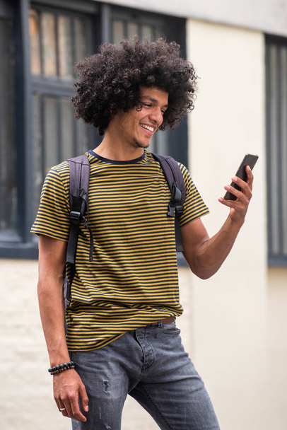 Портрет крутого красивого молодого человека, смотрящего на мобильный телефон
 - Фото, изображение