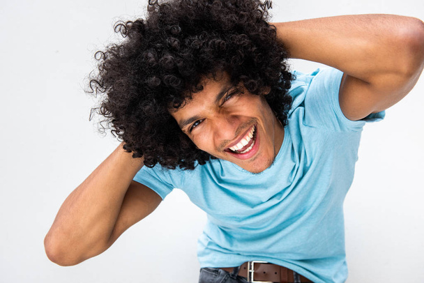 Portrét pohledného mladého muže s afro vlasy smích s rukama za hlavou proti bílému pozadí - Fotografie, Obrázek