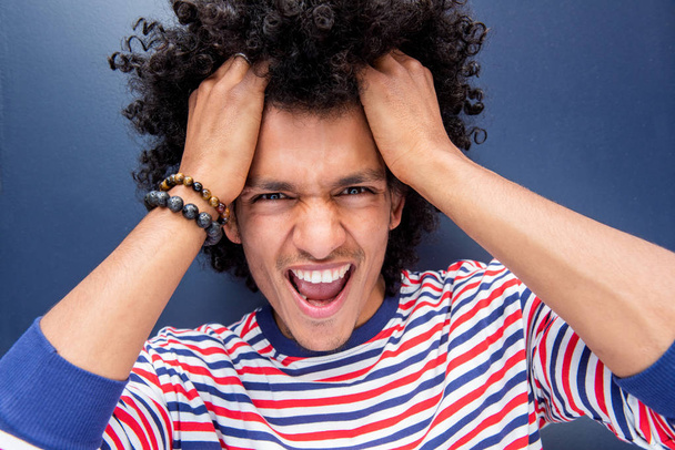 Close up portrait cool young man with mouth open smiling and hands in afro hair  - Фото, изображение