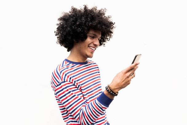 Retrato lateral feliz jovem árabe cara olhando para o celular por fundo branco isolado
 - Foto, Imagem