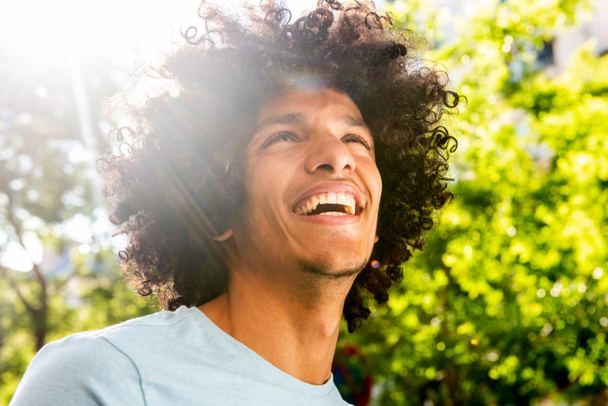Close up portrait handsome young North African man with afro hair laughing outside  - Photo, Image