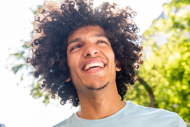 Close up portret przystojny młody Afryki Północnej człowiek z afro włosy uśmiecha się na zewnątrz  - Zdjęcie, obraz