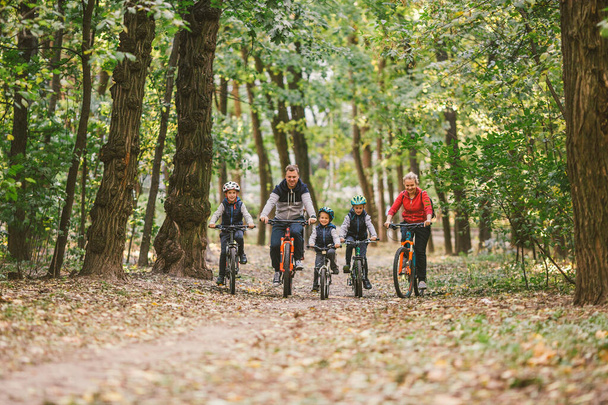 ouders en kinderen fietsen op bospad. Jonge familie fietsen in het najaar park. Familie mountainbiken op bos. Thema familie actieve sport outdoor recreatie. Familie fietsen door het herfstbos - Foto, afbeelding