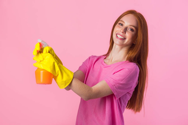 beautiful young woman with red hair in yellow rubber gloves on a pink background - Photo, image