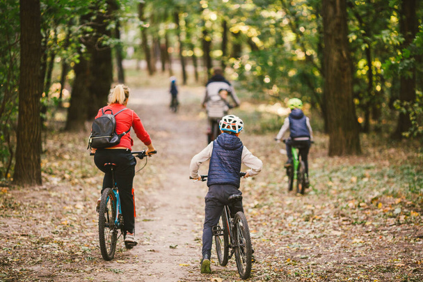 parents et enfants faisant du vélo sur le sentier forestier. Jeune famille à vélo dans le parc d'automne. VTT en famille en forêt. Thème famille sport actif loisirs de plein air. Cyclisme en famille à travers les forêts d'automne
 - Photo, image