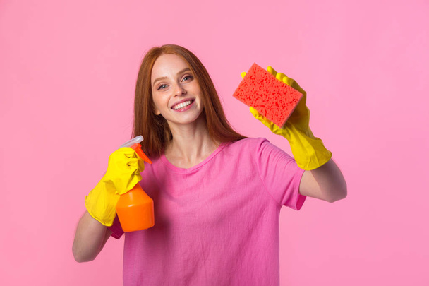 beautiful young woman with red hair in yellow rubber gloves on a pink background - Foto, afbeelding