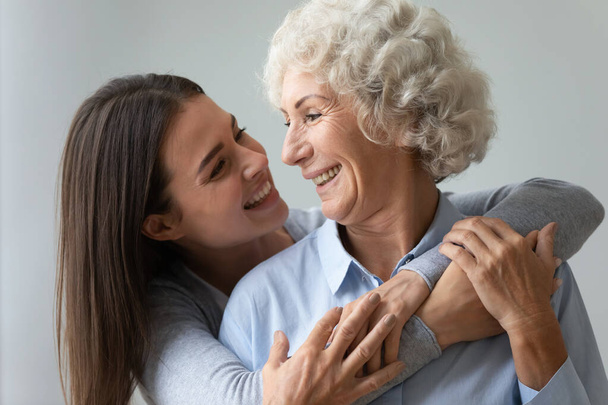 Усміхнена молода жінка онука обіймає щасливу стару бабусю або маму
 - Фото, зображення