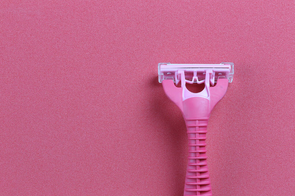 Pink razor on red art paper background. - Zdjęcie, obraz