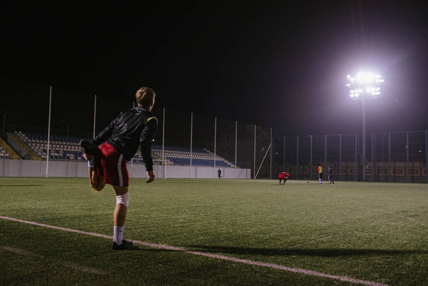 football player doing warm up exercises on the field before the match at night - Photo, image