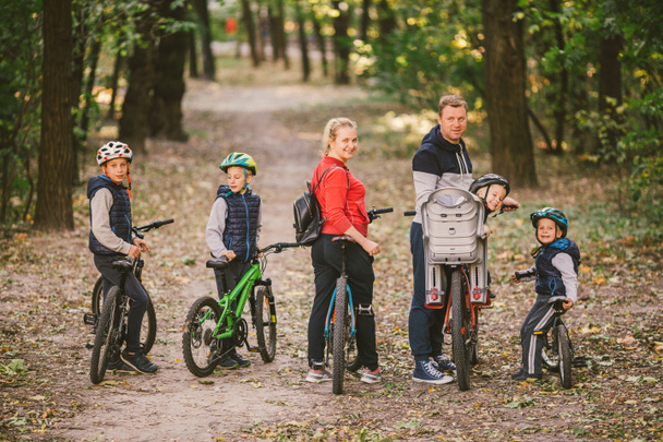Eltern und Kinder radeln auf Waldweg. Familie in warmer Kleidung radelt Herbstpark. Familien-Mountainbike auf Wald. Aktive sportliche Outdoor-Erholung. Porträt Familie radelt durch Herbstwald - Foto, Bild
