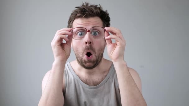 Jeune homme regardant à travers d'énormes lunettes en état de choc avec expression surprise
. - Séquence, vidéo