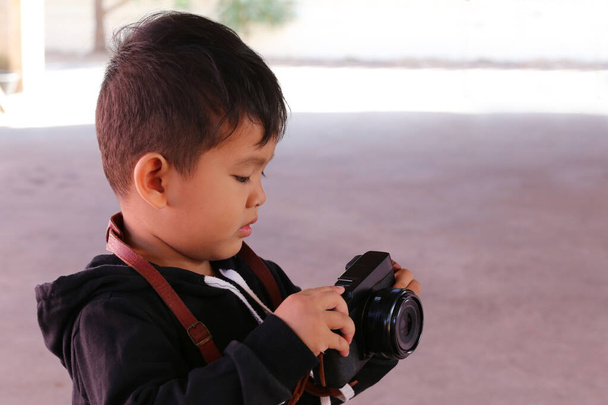 Asiático chico sosteniendo la negro cámara
. - Foto, Imagen