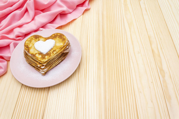 Heart shaped pancakes for romantic breakfast. Shrovetide (carnival) concept. On wooden background with pink linen cloth - Photo, Image