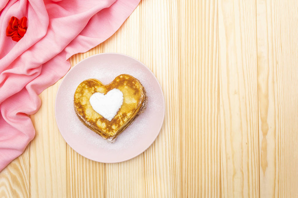 Оладьи в форме сердца для романтического завтрака. Масленица (карнавал) концепция. На деревянном фоне с розовой льняной тканью, вид сверху
 - Фото, изображение