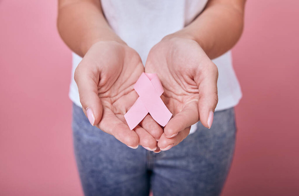 Жінка тримає в руках рожеву стрічку
 - Фото, зображення