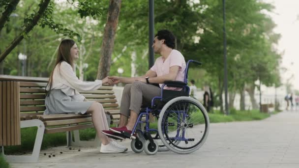 Feliz hombre discapacitado en una silla de ruedas y su novia se encuentra en el parque
 - Metraje, vídeo