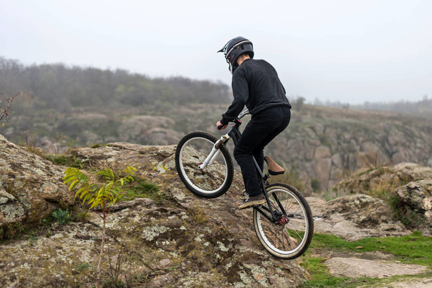 Ciclista en una bicicleta de montaña se eleva por el terreno rocoso
. - Foto, imagen