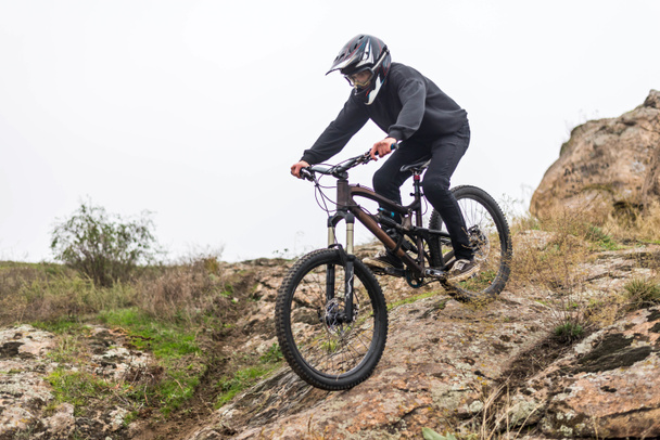 Mountainbiker rijdt een fiets op de rotsen, extreme sport. - Foto, afbeelding