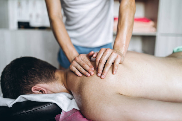 A woman physiotherapist doing back massage for a man in the medi - Foto, Bild