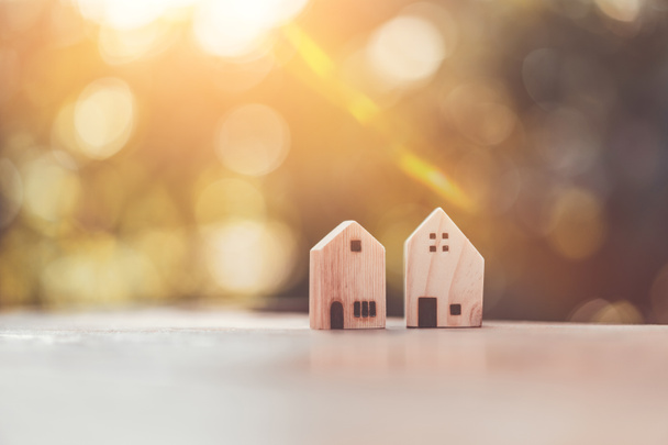 Small model houses on wooden table with nature green bokeh sunlight abstract background. - Photo, Image
