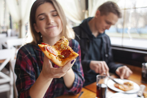 junges Mädchen isst ein Stück Pizza drinnen, Schülerin gibt Pizza, Nahaufnahme - Foto, Bild