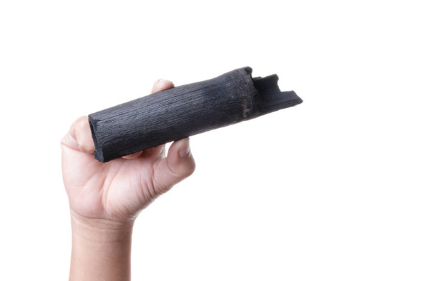 Hand holding natural black wood charcoal made of bamboo use for  - Photo, Image