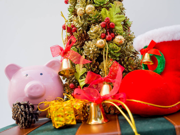白い背景に装飾が施されたクリスマスツリーとピンクの貯金箱、このクリスマスに素敵な休日を過ごしてください - 写真・画像