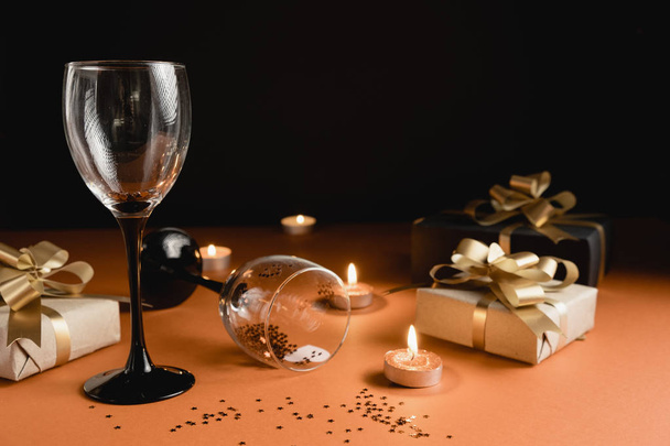 Valentine's Day background. Two clinking wine glasses, various handmade gift boxes decorated with confetti, candle on orange and black background. Valentines day concept. Flat lay, copy space - Fotoğraf, Görsel